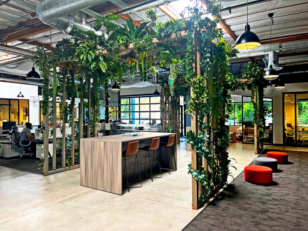 Indoor pergola outfitted with faux plants above employee meeting place