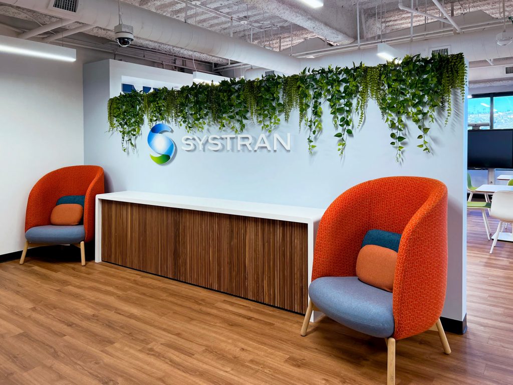 Faux plants cascade over office entry with acrylic logo